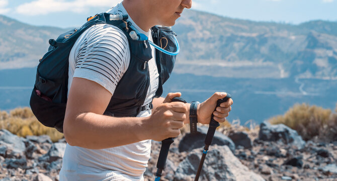 A man with a backpack and trekkikg poles is hiking in the mountains.