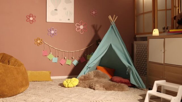Colorful paper notes and beautiful decor hanging on brown wall near toy wigwam in stylish children's room, camera moving forward. Interior design