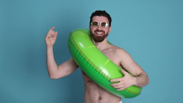Handsome man with inflatable ring on light blue background