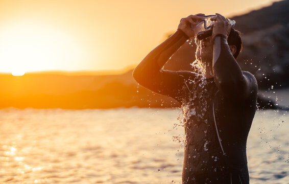 A man is preparing for diving in the ocean at sunset.