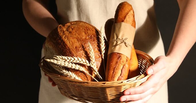 Woman with different types of bread on dark background, closeup