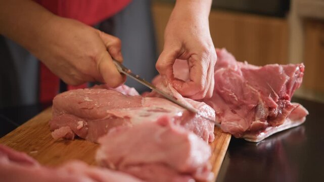 Hands carving pork roast on cutting board, white home cook using serrated knife to slice thin pieces, focused technique and steady blade motion, closeup of texture and juices, kitchen countertop scene