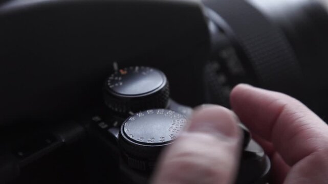 Photographer adjusting shutter speed on analog camera