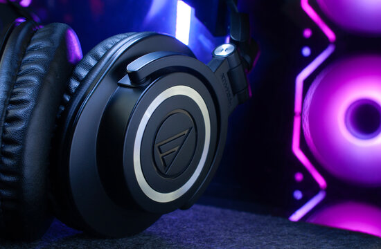 Audifonos de estudio AUDIO TECHNICA en primnr plano con una computadora de escritorio en el fondo y sus ventiladores fuera de foco, para escuchar musica de STREAMERS, editorial o mercadotecnia.