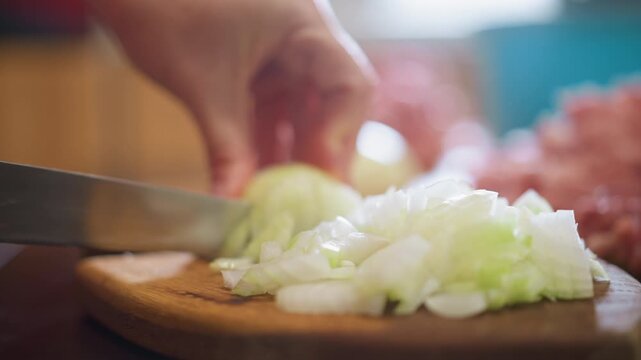Home kitchen closeup chopping onion board, hands slicing green onion on wooden cutting board, raw pork mound blurred in background, warm natural light, shallow depth of field, comforting homestyle