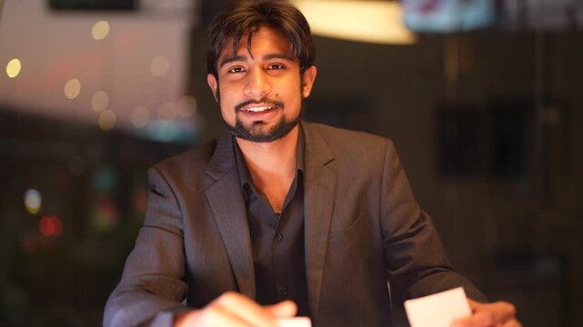 Skilled Indian technical consultant optimizing intricate network frameworks with illuminated skyscraper views in the background within a high end corporate environment.