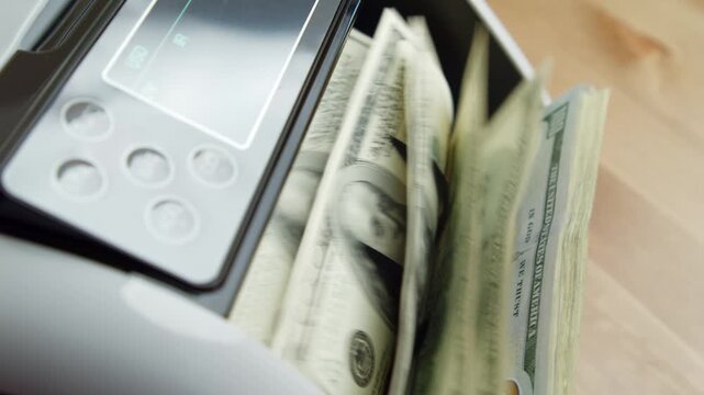 Machine processes stacks of bills efficiently, each note emerging neatly as numbers tally up. Office buzzes with energy as transactions unfold seamlessly
