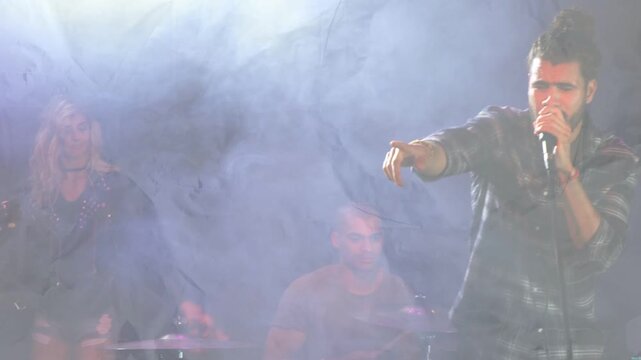 Lead vocalist entering from right moving center pointing into microphone singing and engaging crowd