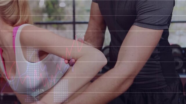 Trainer cueing woman doing kickback, holding arm for form as HUD tracking motion in gym