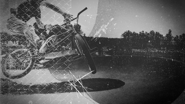 A person performs an acrobatic BMX bike jump in midair captured with a textured vintage black and white effect outdoors.