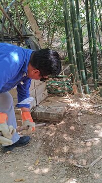 Removing a stuck concrete block using a crowbar and foot leverage