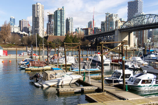 Burrard Civic Marina with docked boats and yachts in front of the downtown Vancouver skyline and Burrard Street Bridge.