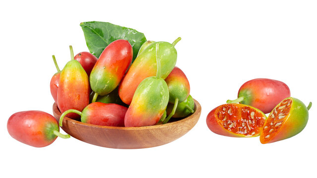 A wooden bowl filled with colorful, ripe ivy gourd fruits alongside sliced pieces revealing red inner pulp.