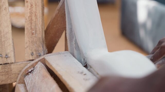 Artisan smoothing wood. Skilled apprentice meticulously smoothing timber during carpentry process demonstration. Focus on young craftsman carefully sanding and finishing wood block professionally
