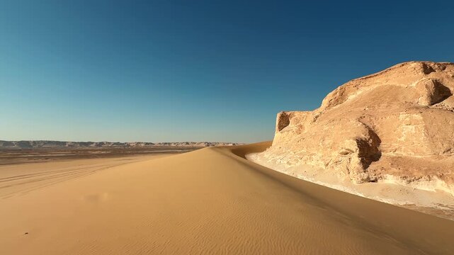 Desert landscape with smooth motion above sand dune near limestone cliff
