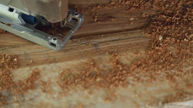 Jigsaw cutting oak plank closeup, meticulous carpentry detail with fine sawdust and narrow groove, steady blade guiding through grain on workshop bench, hobbyist cabinetmaker trimming edge