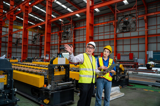 A male chief engineer is instructing female workers on operating machinery in a large factory. The workers are in an industrial plant setting.
Teamwork in an industrial factory.