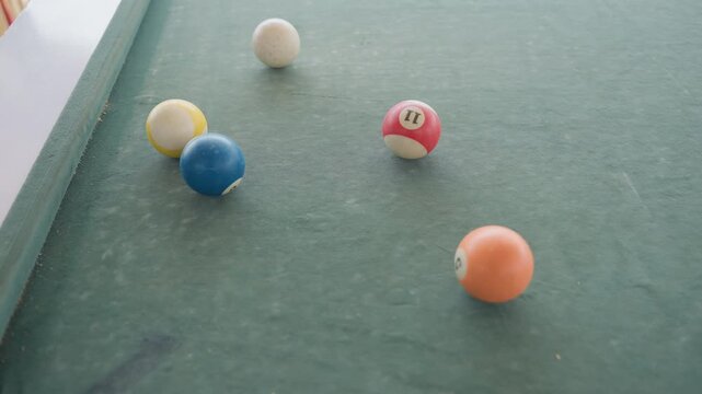 Closeup green felt pool balls rolling across table, soft collision scattering colorful balls, subtle chalk dust on textured surface, natural light and shallow focus creating serene leisure atmosphere