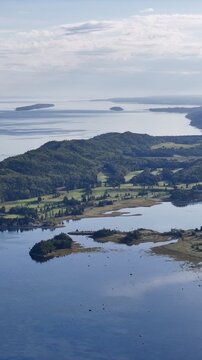 Aerial view of Bic National Park coastline, forest, campground and calm bay under blue sky. g.