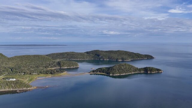 Aerial view of Bic National Park coastline, forest, campground and calm bay under blue sky. g.