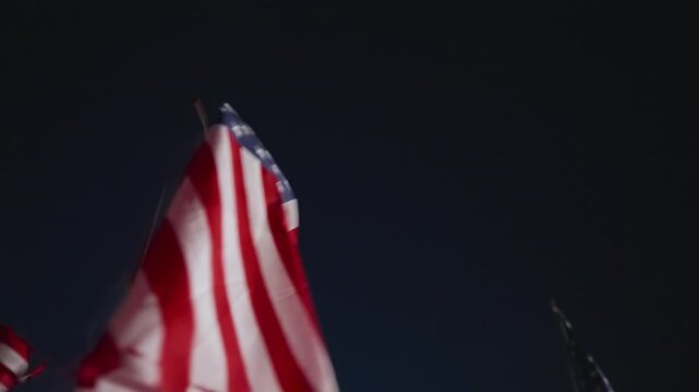 Night American flag waving close view in Malibu, California, USA with strong lighting and motion creating powerful patriotic remembrance scene
