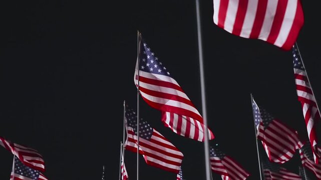 USA flags waving at night in Malibu, California, USA with silhouette person among illuminated memorial creating powerful patriotic tribute atmosphere