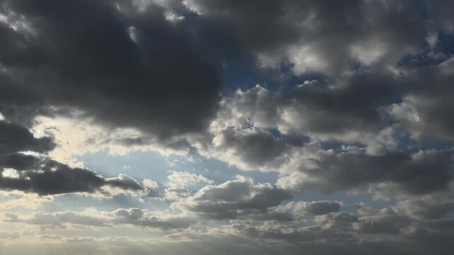 Sunbeams breaking through storm clouds over blue sky, dramatic weather background