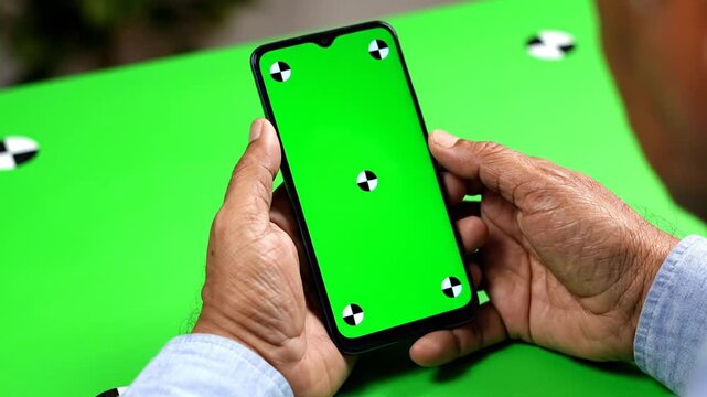 A person holding a smartphone with green screen.