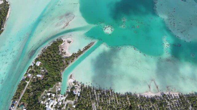 Aerial drone shot of turquoise lagoon in French Polynesia with tropical island, clear blue water and luxury travel destination