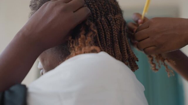 Assistant carefully combs hairstyle in salon. Precise hair trimming and styling captured in professional setting. Focused team collaborates to expertly style and preprocess hair for appointment