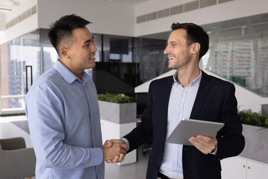 Grateful client shaking hands with consultant manager advisor holding digital tablet in office appreciating help support professional assistance confirming deal agreement built on reliability trust