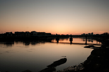 Obraz premium River sunset reflecting city skyline and bridge at dusk