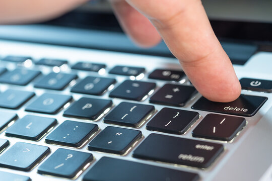 Finger of the computer user, he presses the delete button on the computer keyboard.	
