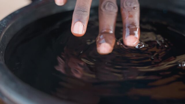 Multiple fingers dipping into dark stain, carpentry apprentice testing varnish alongside mentor, collaborative hands creating ripples and droplets on glossy surface, tactile quality check for wood