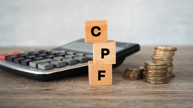 Vertical stack of wooden blocks spelling CPF with calculator and coin piles.