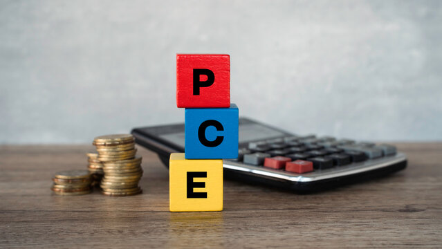 PCE Personal Consumption Expenditures index concept with wooden blocks calculator and coins on wooden desk
