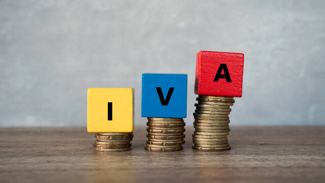 IVA Value Added Tax acronym on wooden blocks placed on stacks of coins representing taxation and finance