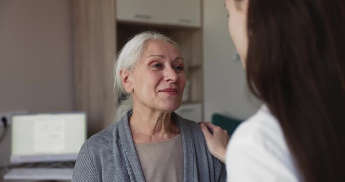 Smiling senior woman patient talking to doctor, listening professional advices, treatment plan explanation, health recommendations during medical consultation in clinic. Healthcare services, checkup