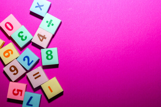 Bright multicolored cubes with numbers and arithmetic symbols are scattered on a rich pink background, leaving free space for text on the right.