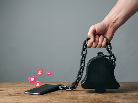 Social media addiction concept with smartphone chained to heavy weight and notification icons