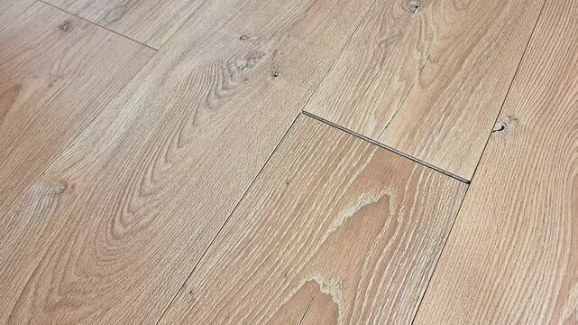 Light brown wooden floor with visible grain patterns and seams between planks, highlighting natural texture, smooth finish, and timeless detail of wood material