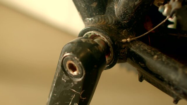 Closeup crank spindle pedal arm scratched paint aged bearing, torque test producing creak and clack, mechanic inspects wear, objects make sound revealing vintage history