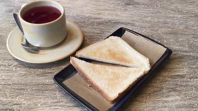cup of red tea with toasted bread on rustic wooden table hand touching cup cozy cafe drink closeup simple composition warm light concept of cafe business restaurant hospitality