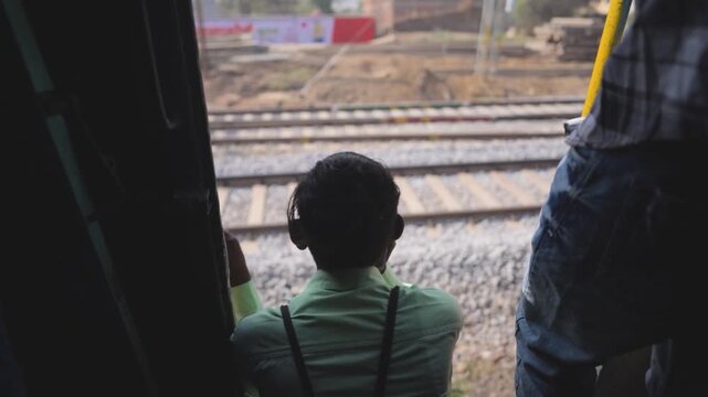 boy sitting at train door, man watching railway tracks, train journey door side view, kid travel moment in train stock video.