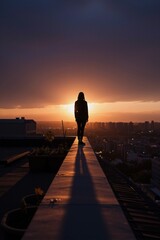 Fototapeta premium A solitary figure stands at the rooftop's edge, lost in thought as sunset casts warm golden hues over the cityscape.