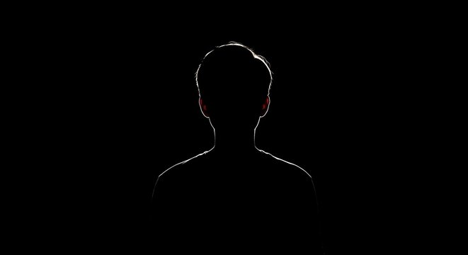 A mysterious silhouette of a person's head and shoulders outlined by light against a dark, black background, evoking anonymity and introspection.