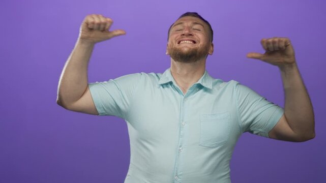 Young caucasian man with thumbs pointing to chest and wide open mouth in purple studio; confidence celebration.