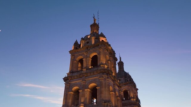 Cathedral Basilica of the Immaculate Conception in Durango, Mexico illuminated at sunset. Twin bell towers with ornate baroque architecture rise against blue twilight sky with warm golden lighting.