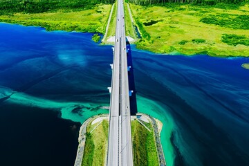 Naklejka premium Aerial View of a Modern Bridge Spanning Over a Serene Body of Water Surrounded by Lush Greenery