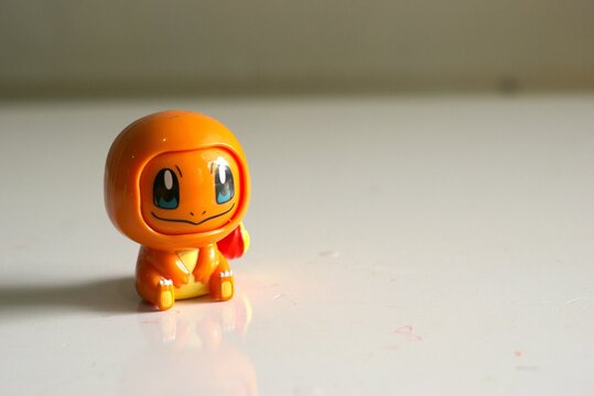 charmander pokemon figurine on a white reflective surface
